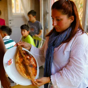 A guest holding a plated Calzone Dolce at the table.